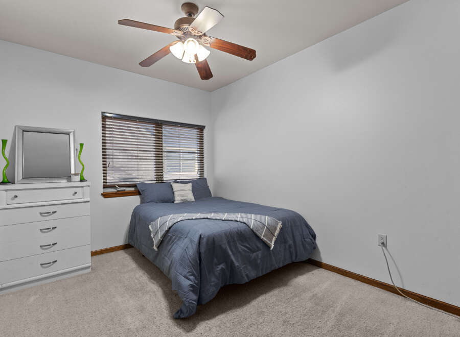 This cozy bedroom features a comfortable bed with a stylish blue comforter and a decorative throw blanket.