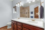 This stunning bathroom features a double vanity with a sleek white countertop and rich wooden cabinetry, offering ample storage and a touch of elegance.