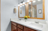 This beautiful bathroom features a double vanity with a bright white countertop and rich wood cabinetry.