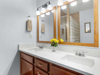 This beautiful bathroom features a double vanity with a bright white countertop and rich wood cabinetry.