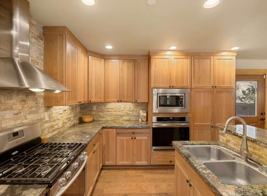 This stunning kitchen boasts custom cabinetry, stainless steel appliances, and a beautiful stone backsplash.