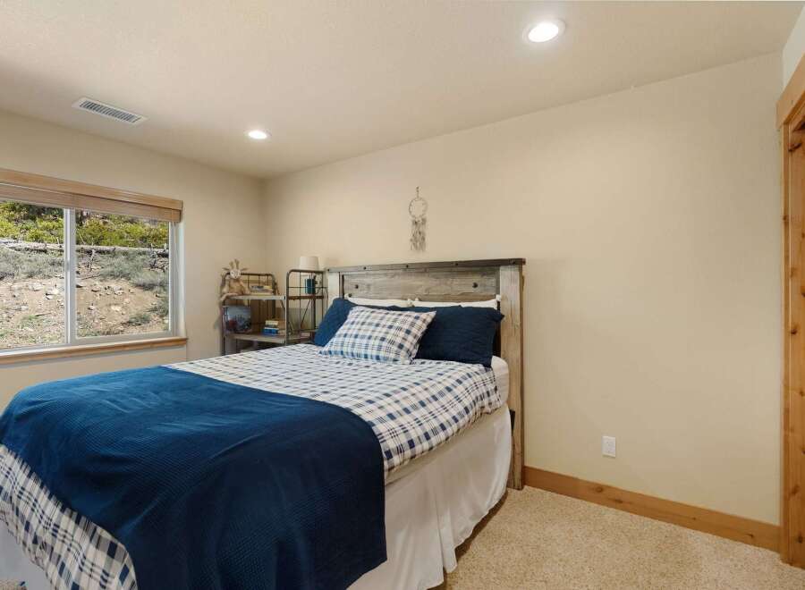 This cozy bedroom features a rustic wooden headboard and a comfortable bed with a plaid comforter.