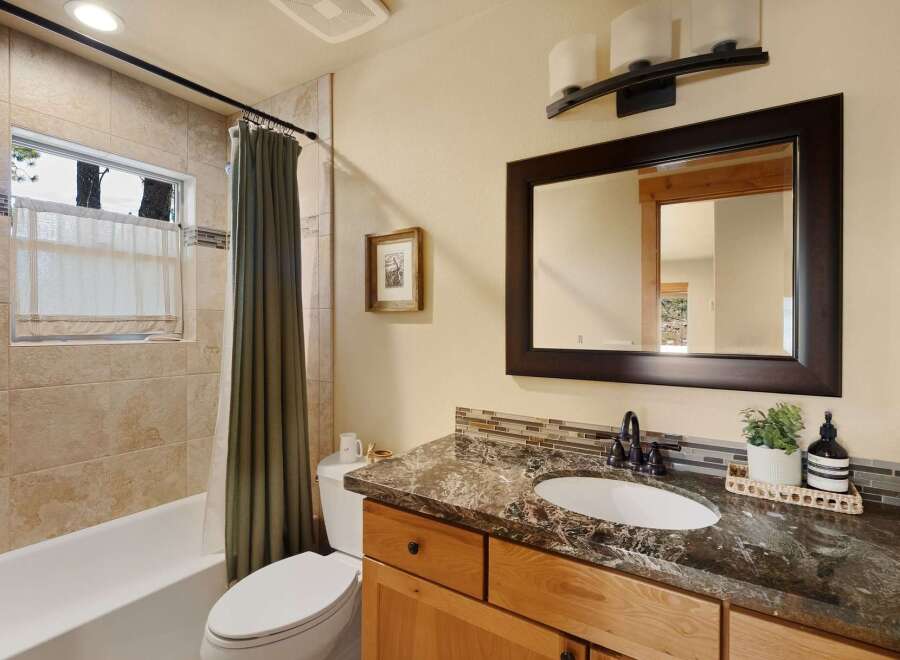 This beautiful bathroom features a modern vanity with a dark countertop and a large mirror.
