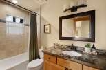 This beautiful bathroom features a modern vanity with a dark countertop and a large mirror.