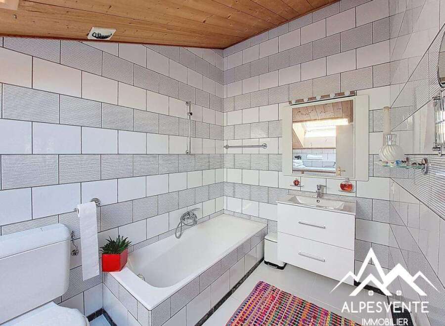 This charming bathroom features a modern design with white tiles and a bathtub.