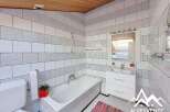 This charming bathroom features a modern design with white tiles and a bathtub.