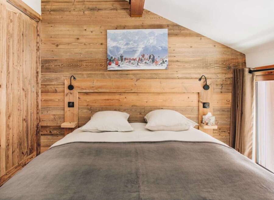This cozy bedroom features a rustic wooden wall and headboard, creating a warm and inviting atmosphere.