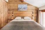 This cozy bedroom features a rustic wooden wall and headboard, creating a warm and inviting atmosphere.