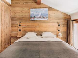 This cozy bedroom features a rustic wooden wall and headboard, creating a warm and inviting atmosphere.