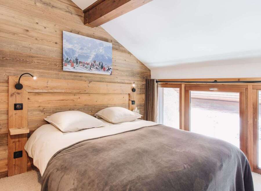 This cozy bedroom features a rustic wooden wall and a comfortable bed, creating a warm and inviting atmosphere.