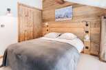 Experience rustic charm in this cozy bedroom featuring a wooden headboard and paneling.
