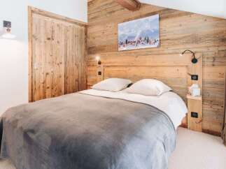 Experience rustic charm in this cozy bedroom featuring a wooden headboard and paneling.