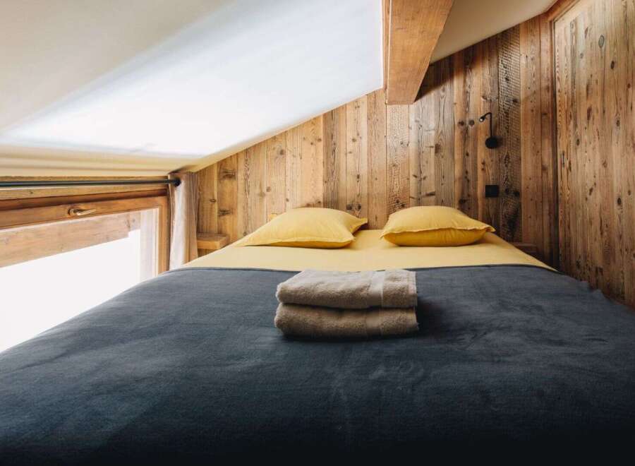 This cozy bedroom features a rustic wooden wall and a comfortable bed, perfect for a relaxing getaway.
