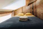 This cozy bedroom features a rustic wooden wall and a comfortable bed, perfect for a relaxing getaway.