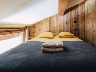 This cozy bedroom features a rustic wooden wall and a comfortable bed, perfect for a relaxing getaway.