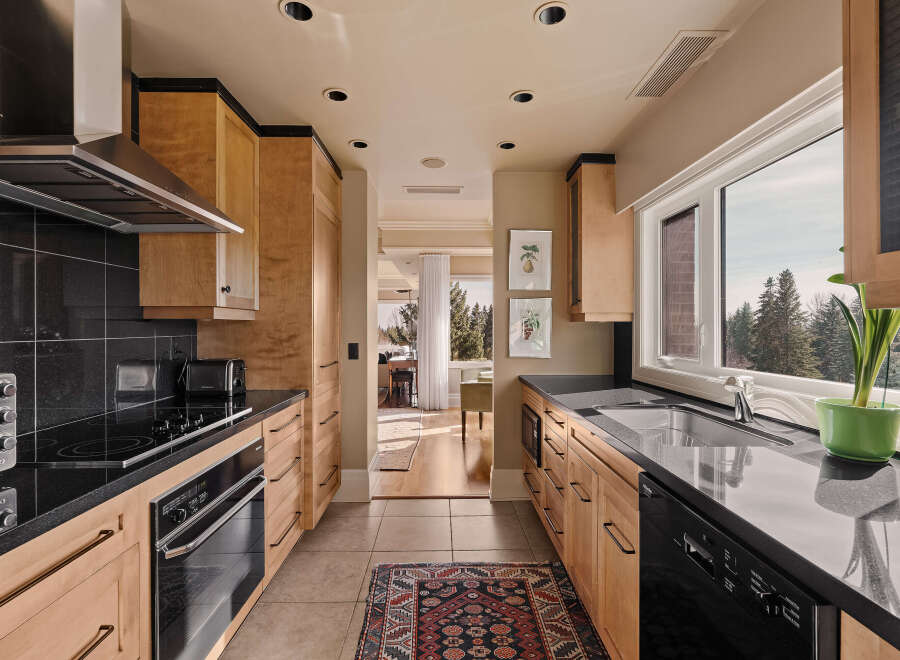 This stunning kitchen boasts sleek black countertops and modern appliances, creating a sophisticated cooking space.