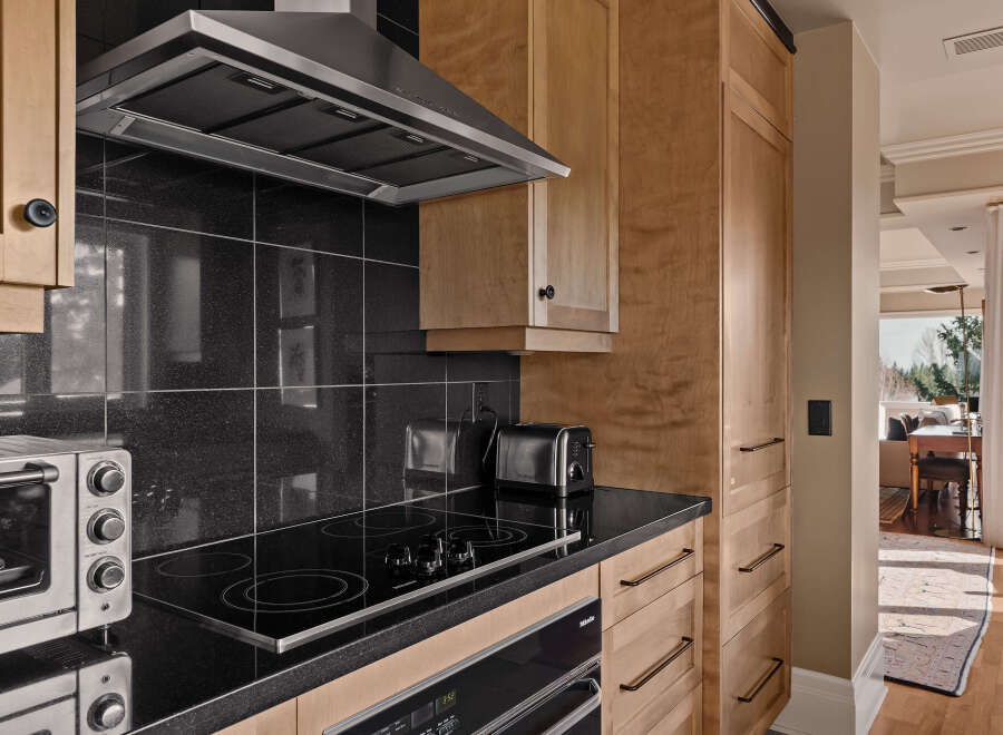 This stunning kitchen boasts sleek black countertops and modern appliances, perfect for culinary enthusiasts.