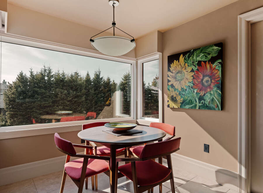 This dining area is bathed in natural light, thanks to the expansive windows that offer stunning views of the surrounding greenery.