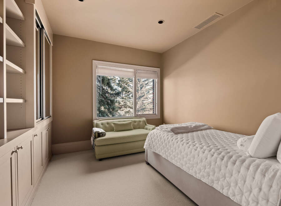 This elegant bedroom offers a serene retreat with its neutral color palette and ample natural light.