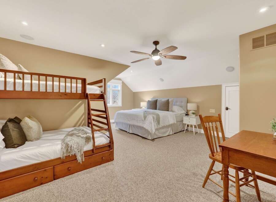 This spacious bedroom features a cozy bunk bed and a comfortable queen-sized bed, perfect for accommodating guests or family.