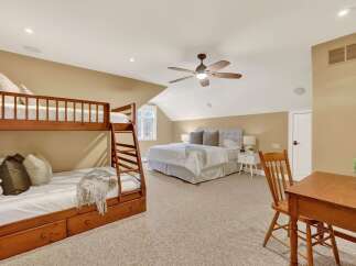 This spacious bedroom features a cozy bunk bed and a comfortable queen-sized bed, perfect for accommodating guests or family.