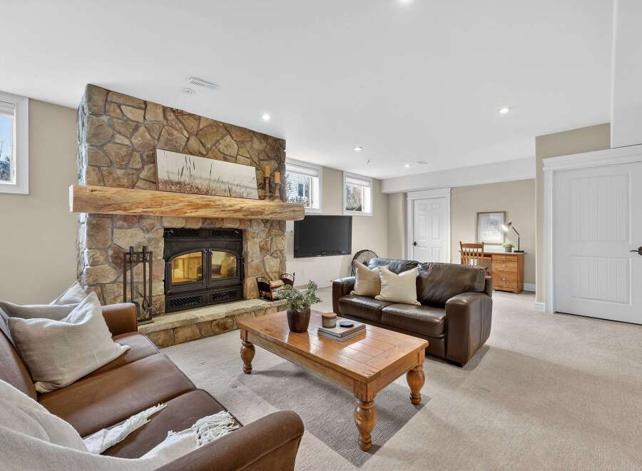 This stunning living room boasts a cozy fireplace with a stone facade and a rustic wooden mantel, creating a warm and inviting atmosphere.