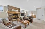 This stunning living room boasts a cozy fireplace with a stone facade and a rustic wooden mantel, creating a warm and inviting atmosphere.