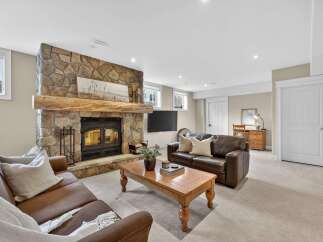 This stunning living room boasts a cozy fireplace with a stone facade and a rustic wooden mantel, creating a warm and inviting atmosphere.