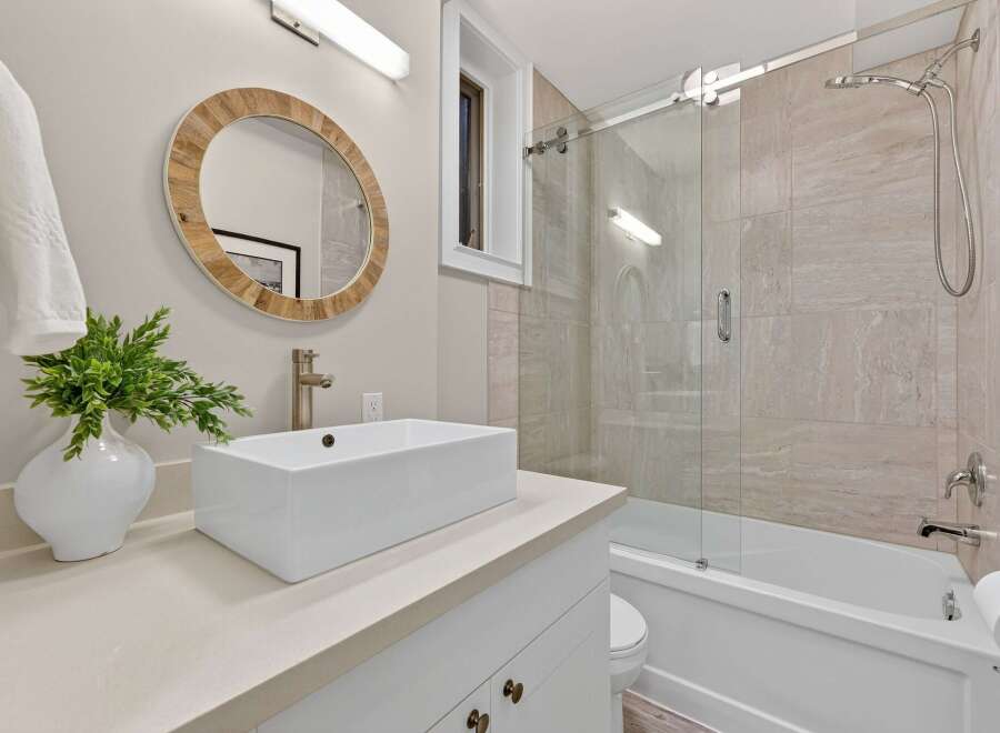 This stunning bathroom boasts a modern design with a sleek, rectangular sink and a stylish, round mirror.