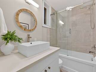 This stunning bathroom boasts a modern design with a sleek, rectangular sink and a stylish, round mirror.