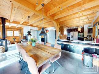 Experience the charm of this stunning property, featuring a spacious dining area with a rustic wooden table and elegant chairs.