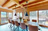 Experience the charm of this stunning property, featuring a spacious dining area with a rustic wooden table and stylish chairs.