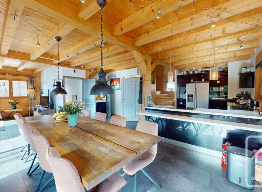 Experience the charm of this stunning property, featuring a spacious dining area with a rustic wooden table and elegant pendant lighting.