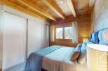 Discover the charm of this cozy bedroom, featuring a warm wooden ceiling and walls that create a rustic ambiance.