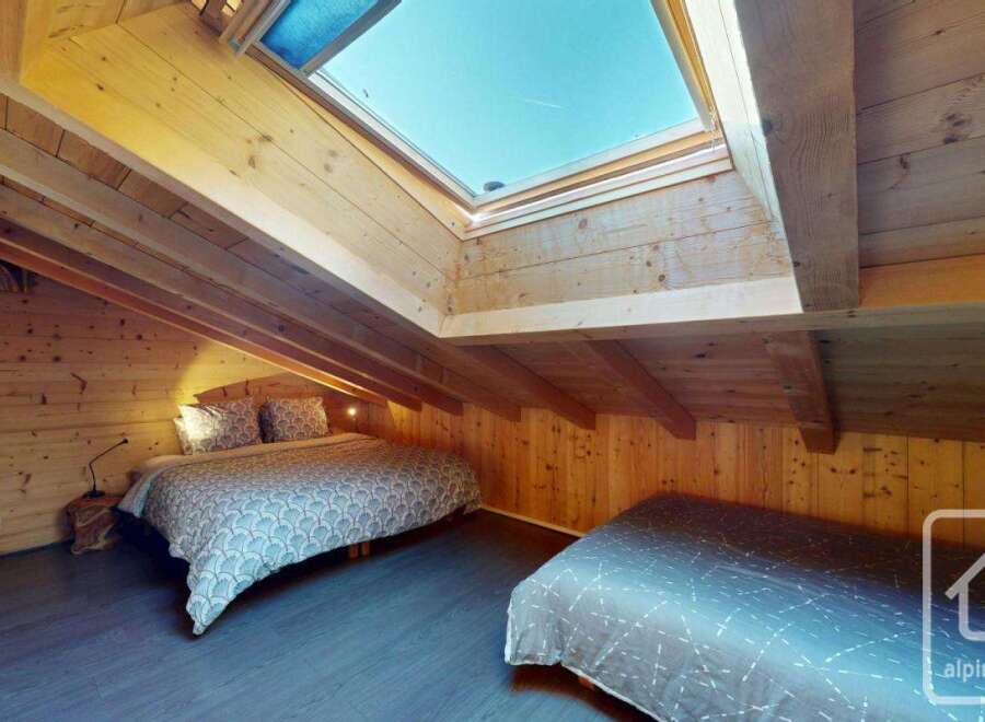 Discover the charm of this cozy bedroom, featuring a unique sloped ceiling and natural wood accents.