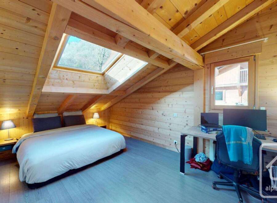 Discover the charm of this cozy bedroom, featuring a unique sloped ceiling and natural wood accents.