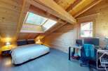 Discover the charm of this cozy bedroom, featuring a unique sloped ceiling and natural wood accents.