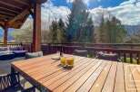 Enjoy breathtaking views from this stunning property! This outdoor space features a beautiful wooden table, perfect for dining al fresco.