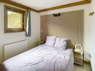Discover the charm of this cozy bedroom, featuring a stylish wooden headboard and a comfortable bed.