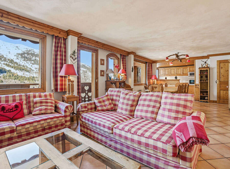 Experience the charm of this cozy chalet, featuring a spacious living area with a comfortable sofa and a stunning view of the snowy mountains.