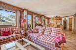 Experience the charm of this cozy chalet, featuring a spacious living area with a comfortable sofa and a stunning view of the snowy mountains.