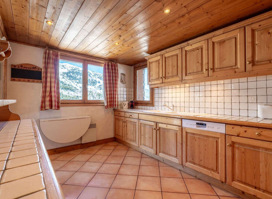 This charming kitchen boasts a warm, inviting atmosphere with its wooden cabinets and ceiling.