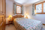 This charming bedroom features a cozy double bed adorned with a floral patterned quilt, creating a warm and inviting atmosphere.