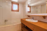 This charming bathroom features a classic design with a wooden vanity and a bright, airy feel.