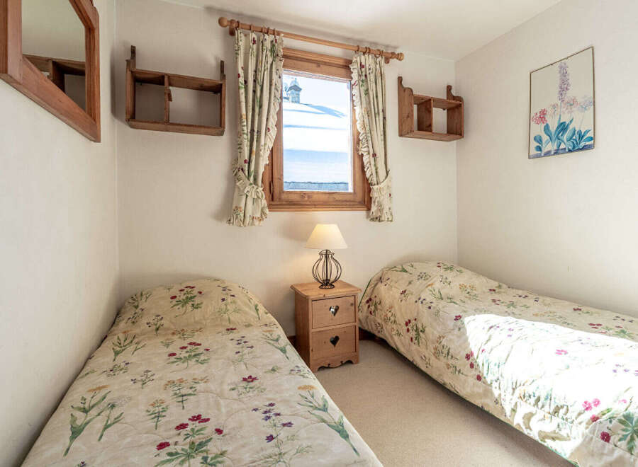 This charming bedroom features two twin beds with floral bedding, perfect for a cozy retreat.