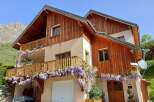 Discover the charm of this stunning property, featuring a beautiful wooden facade and a welcoming balcony adorned with vibrant flowers.
