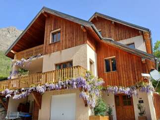 Discover the charm of this stunning property, featuring a beautiful wooden facade and a welcoming balcony adorned with vibrant flowers.