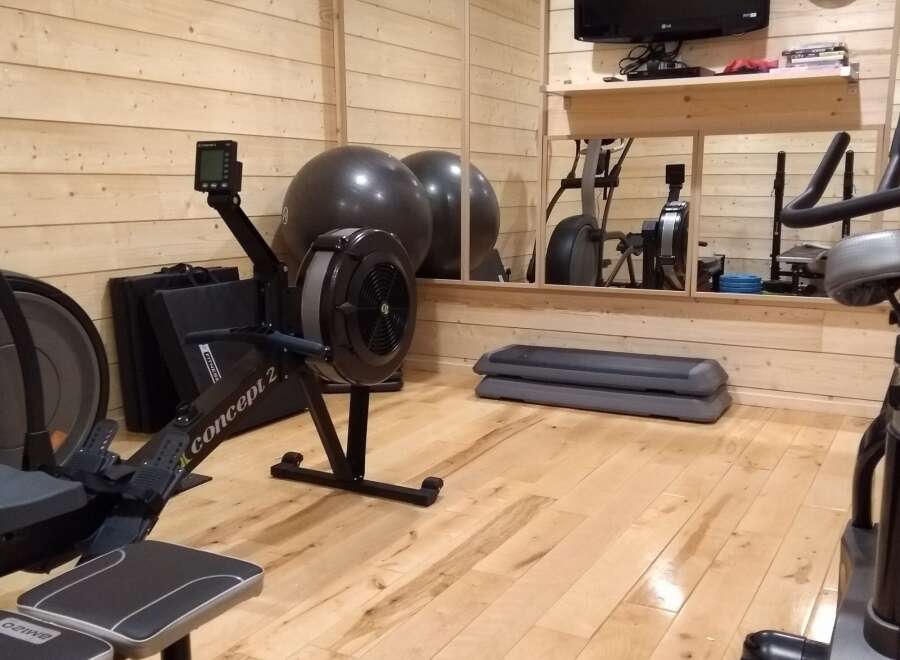 This home gym is perfect for staying in shape, featuring a Concept 2 rower, exercise balls, and a step platform.