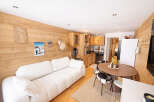 This charming property features a cozy living space with a comfortable white sofa and a warm wooden interior.