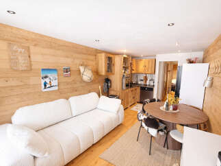 This charming property features a cozy living space with a comfortable white sofa and a warm wooden interior.